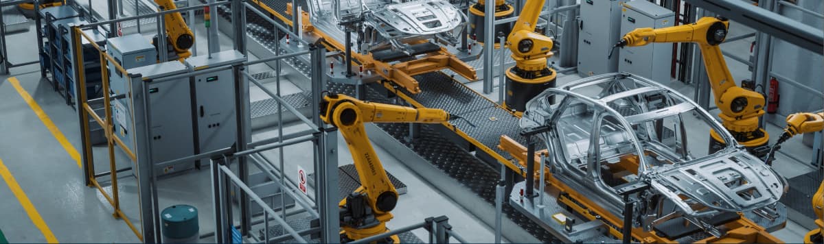 Robotic arms assembling car body frames on an automated production line inside a modern automotive facility
