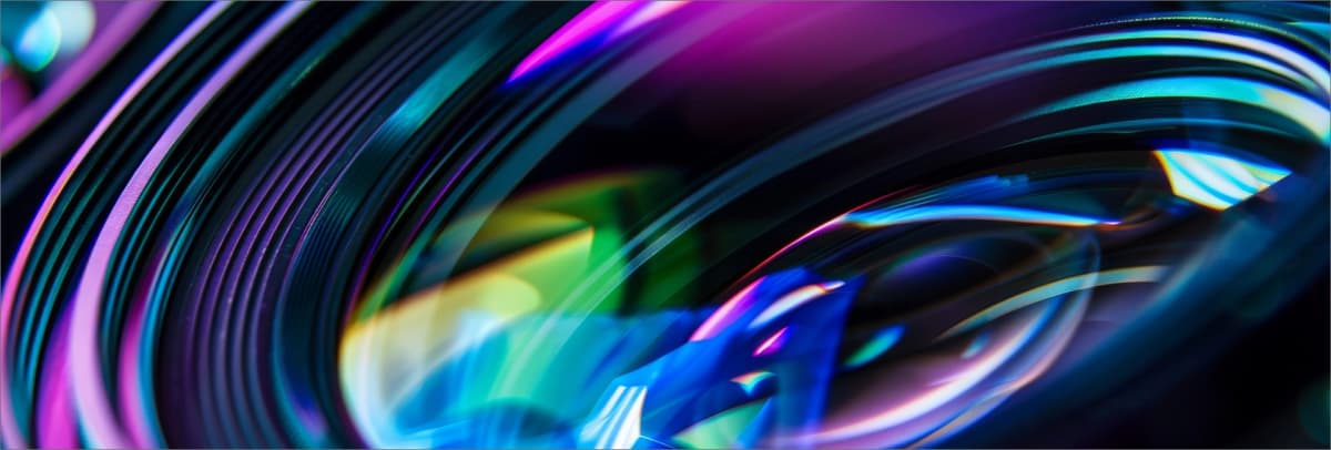 Abstract neon waves in pink, blue, and green flowing across a dark background with smooth motion blur effects